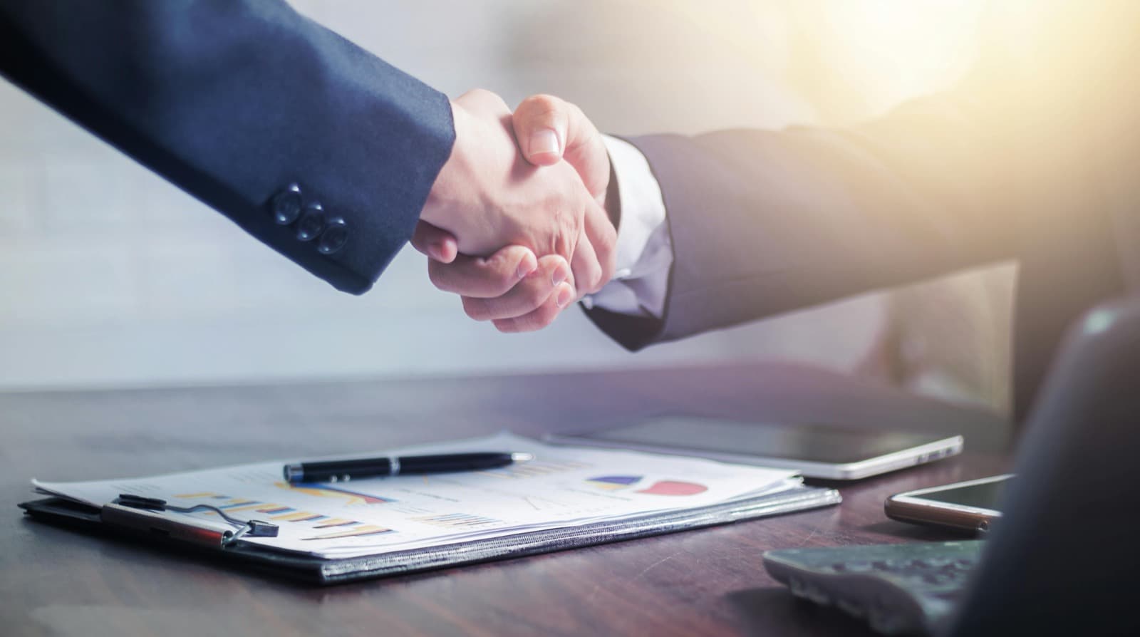 Attorney and client shaking hands over a desk with documents